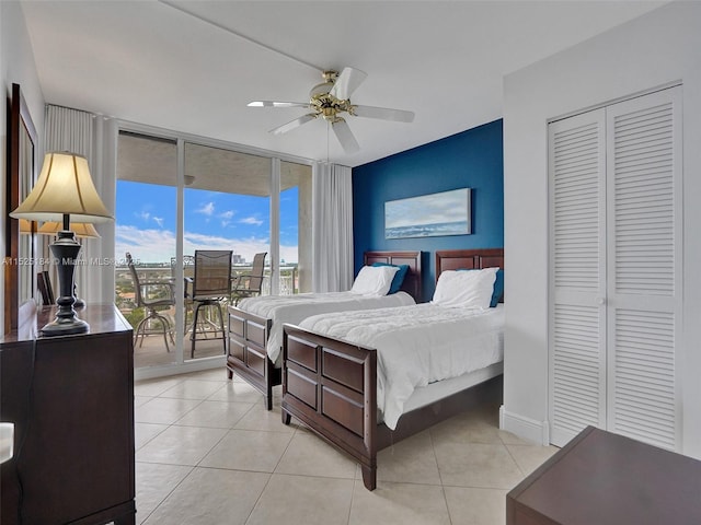 bedroom with a ceiling fan, light tile patterned flooring, a wall of windows, access to outside, and baseboards