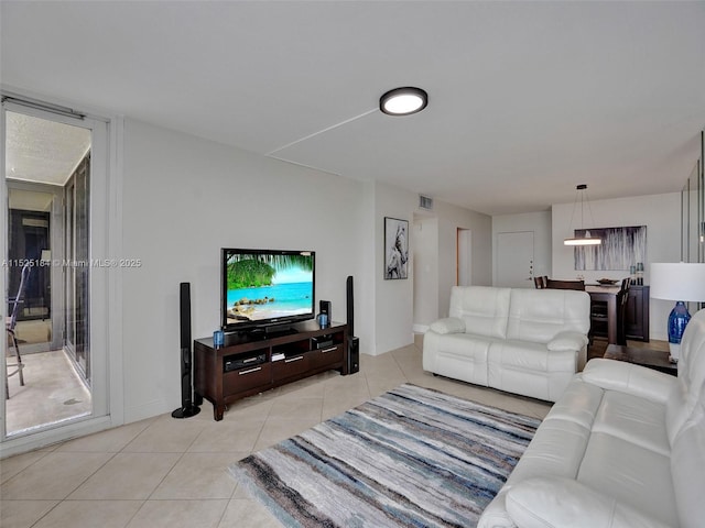 living area featuring plenty of natural light, light tile patterned floors, baseboards, and visible vents