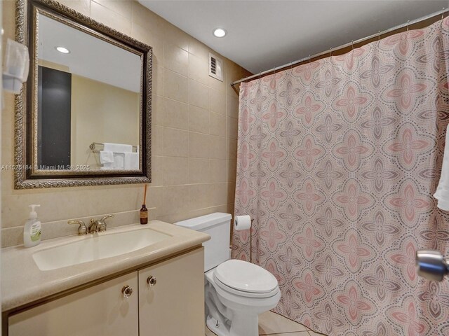 bathroom with tile patterned flooring, vanity, tile walls, and toilet