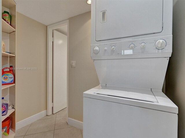 clothes washing area featuring light tile patterned flooring and stacked washer / dryer