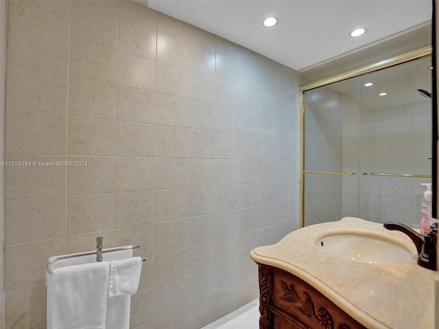 bathroom featuring vanity, a shower with door, and tile walls