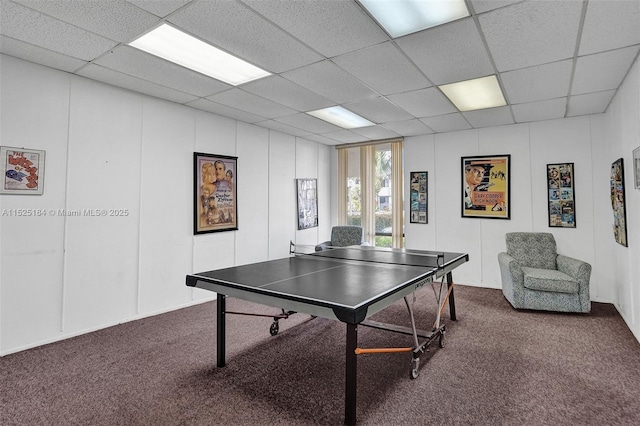 game room featuring dark colored carpet, a drop ceiling, and a decorative wall