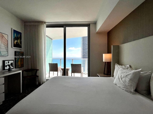 bedroom with a water view, access to exterior, and expansive windows