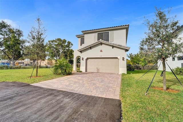 view of front of home featuring stucco siding, an attached garage, a front lawn, and decorative driveway