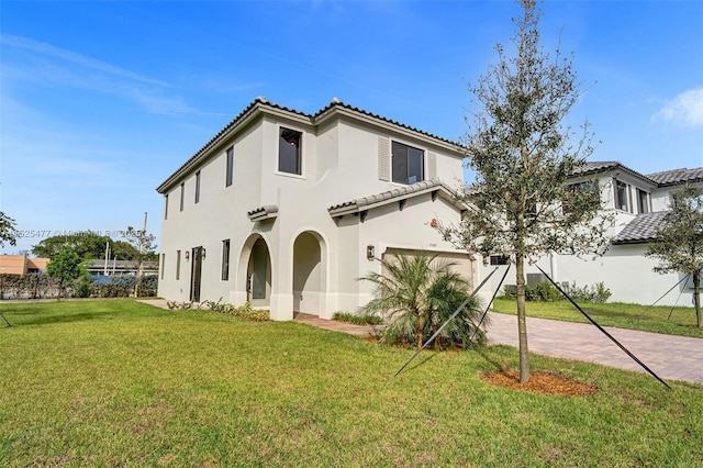 mediterranean / spanish-style home featuring a front lawn, stucco siding, an attached garage, a tile roof, and decorative driveway