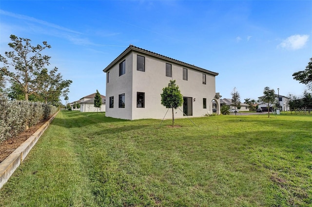rear view of property featuring a lawn and stucco siding