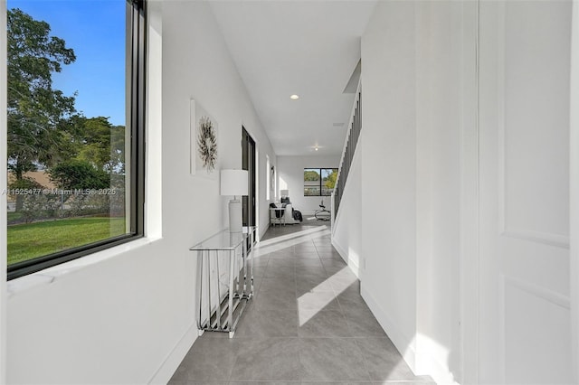 hallway with baseboards, recessed lighting, an upstairs landing, and light tile patterned floors