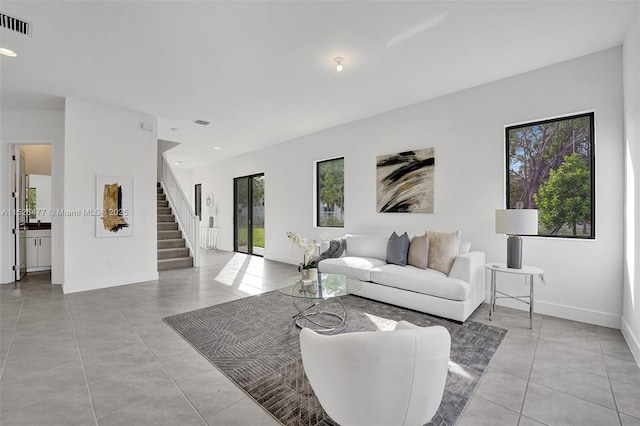 living area featuring stairway, light tile patterned floors, baseboards, visible vents, and recessed lighting