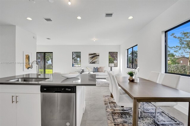 kitchen featuring light tile floors, white cabinetry, dishwasher, and sink