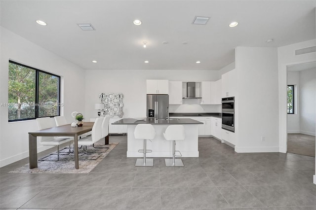 kitchen featuring wall chimney exhaust hood, stainless steel appliances, visible vents, and plenty of natural light