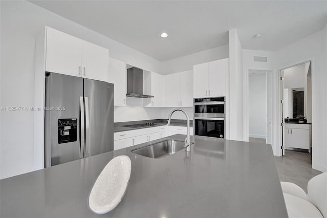 kitchen featuring stainless steel appliances, visible vents, a sink, wall chimney exhaust hood, and white cabinetry