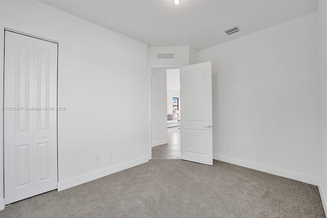 unfurnished bedroom featuring carpet floors, a closet, visible vents, and baseboards