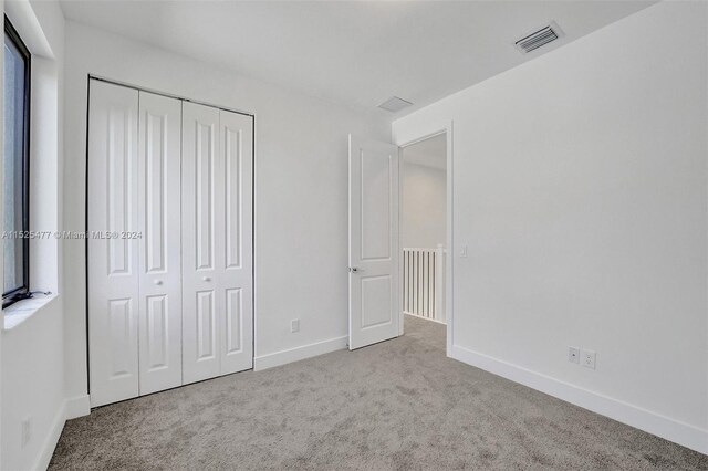 unfurnished bedroom featuring a closet and light colored carpet