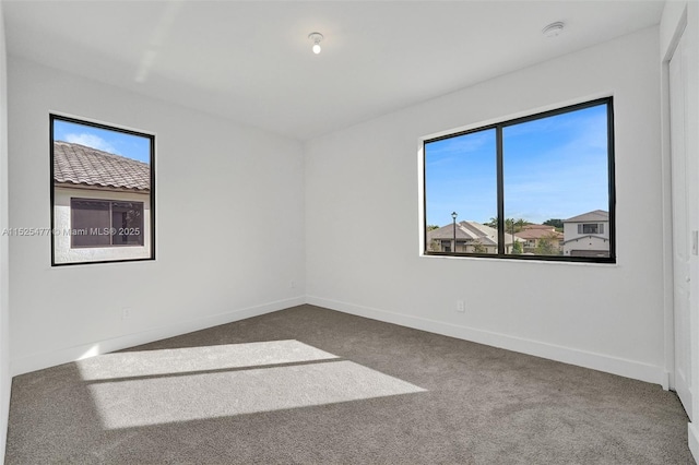 carpeted spare room featuring baseboards