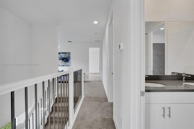 corridor featuring light colored carpet and sink