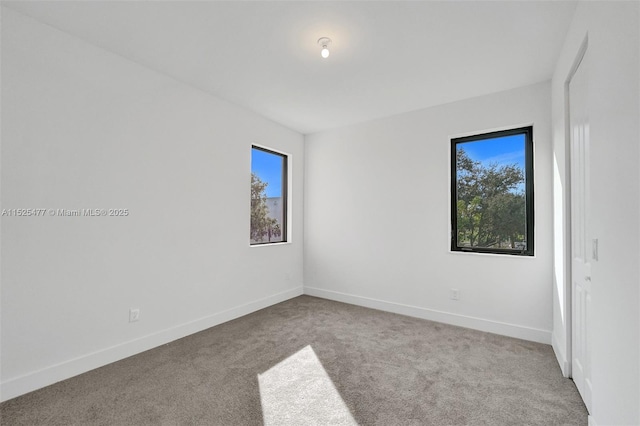 carpeted empty room featuring plenty of natural light and baseboards
