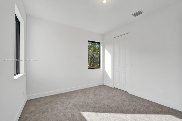 unfurnished room with baseboards, carpet flooring, and visible vents