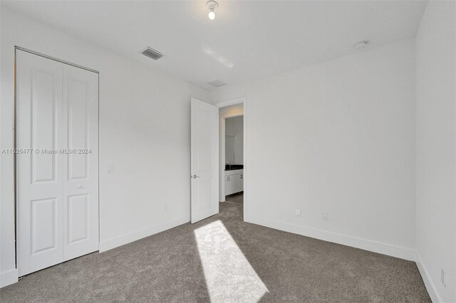 unfurnished bedroom with a closet and dark colored carpet