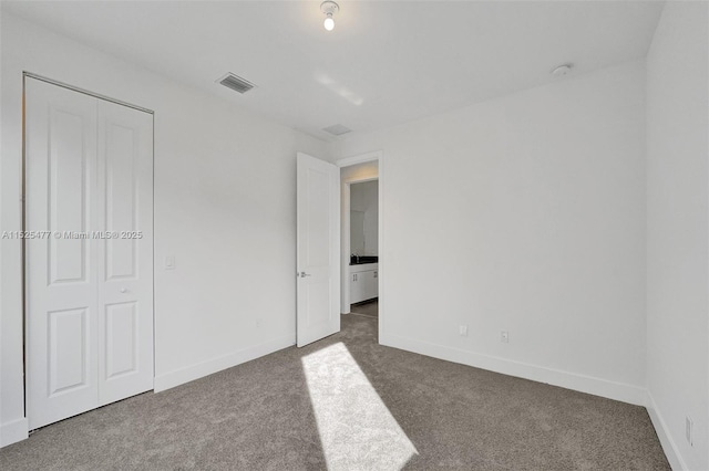 unfurnished bedroom featuring dark carpet, visible vents, and baseboards
