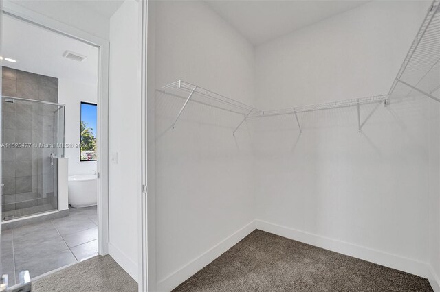 walk in closet with light tile floors