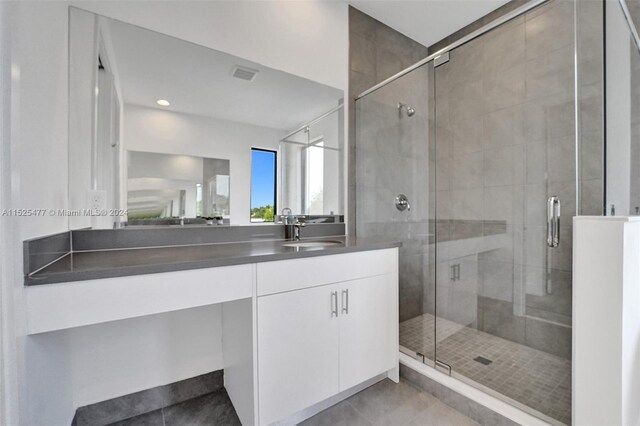 bathroom featuring a shower with door, tile flooring, and vanity