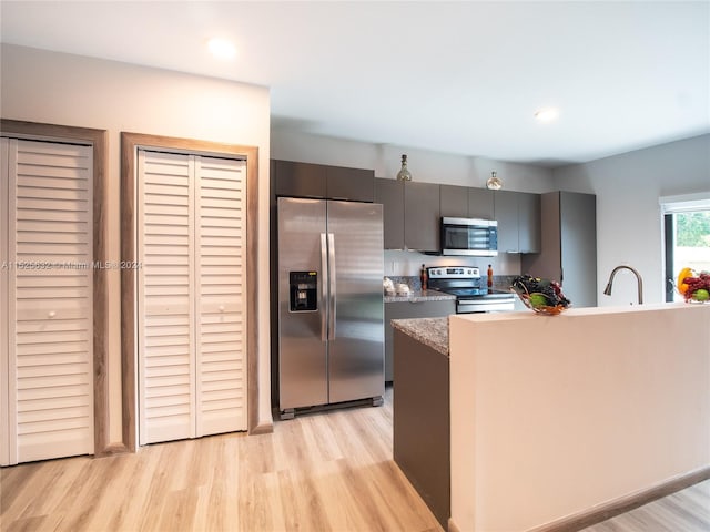 kitchen with appliances with stainless steel finishes, sink, and light wood-type flooring