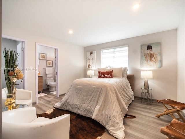 bedroom featuring connected bathroom and light hardwood / wood-style flooring