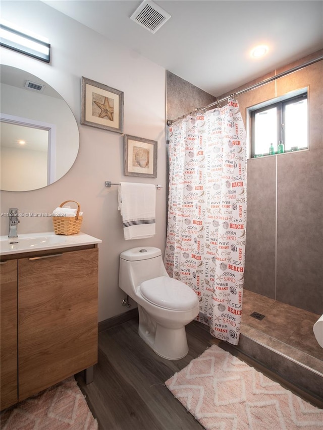 bathroom with a shower with shower curtain, toilet, vanity with extensive cabinet space, and hardwood / wood-style flooring