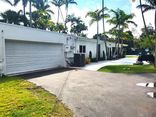 rear view of property featuring a garage and central AC unit