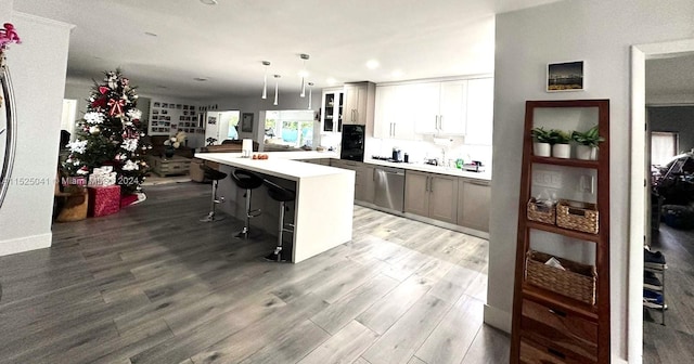 kitchen featuring pendant lighting, dishwasher, a breakfast bar area, white cabinets, and light wood-type flooring