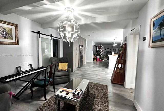 living room with a barn door, hardwood / wood-style floors, and an inviting chandelier