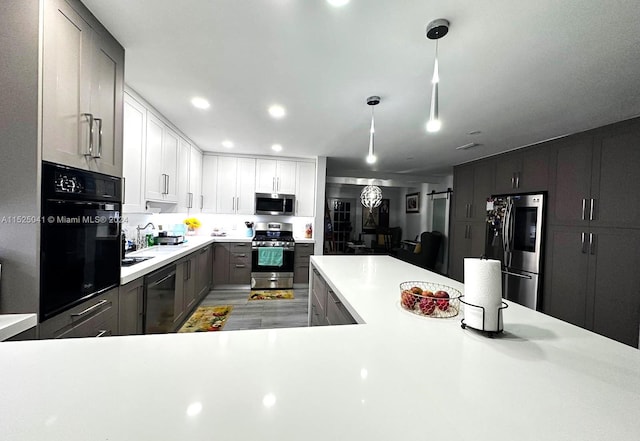 kitchen featuring hanging light fixtures, stainless steel appliances, and white cabinets