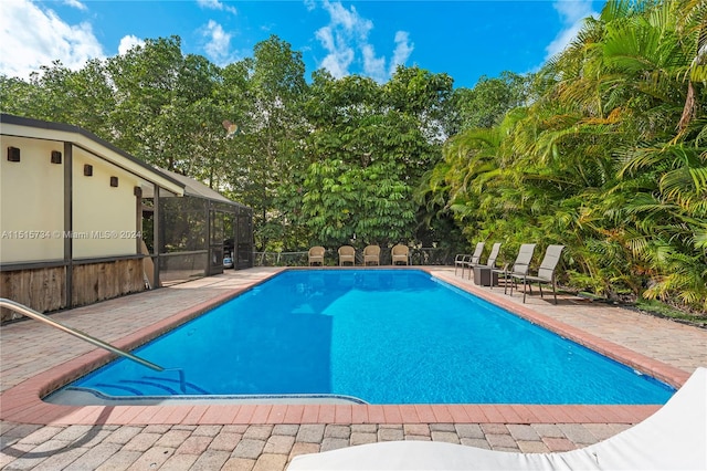 view of swimming pool with a patio area and glass enclosure