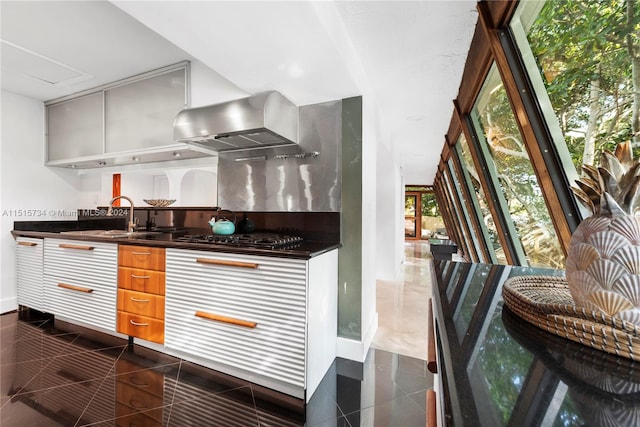 kitchen with range hood, dark tile floors, sink, and black gas cooktop