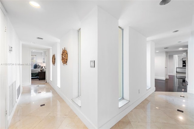 hallway featuring plenty of natural light and light tile floors