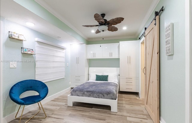 bedroom with a barn door, crown molding, ceiling fan, and light hardwood / wood-style flooring