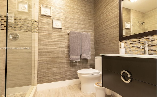 bathroom featuring tile walls, toilet, a tile shower, and vanity