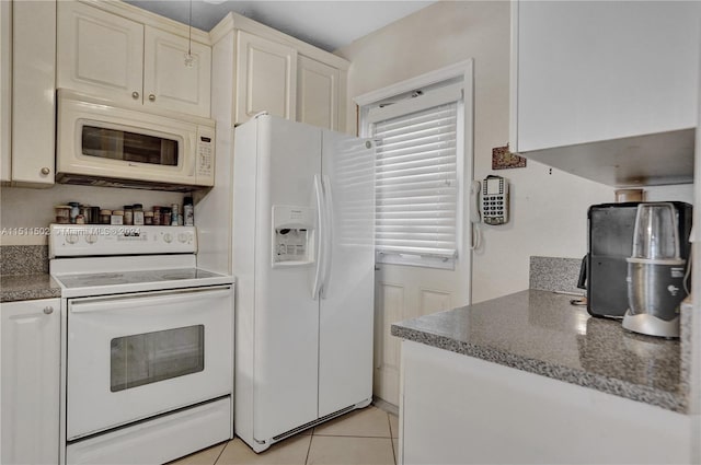 kitchen featuring white appliances, dark stone counters, and light tile flooring