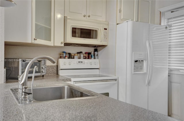 kitchen featuring white cabinets, sink, white appliances, and light stone countertops