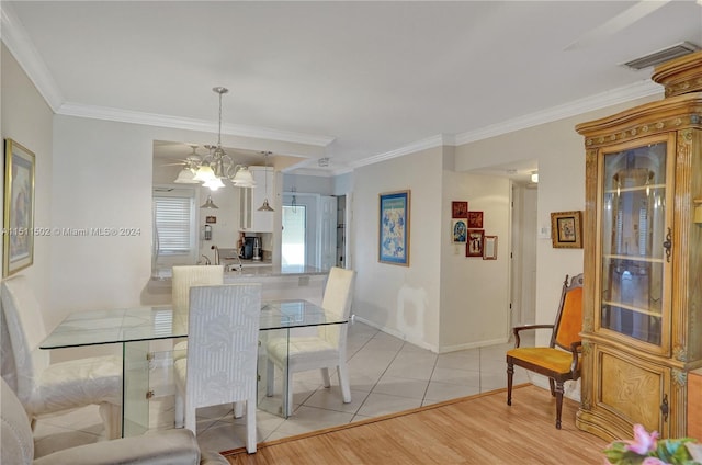 dining space featuring light tile flooring, crown molding, and an inviting chandelier