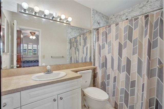 bathroom with ceiling fan, vanity with extensive cabinet space, and toilet