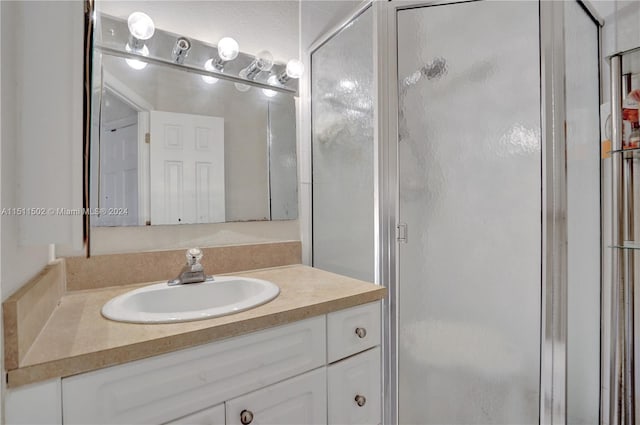 bathroom with a shower with shower door and vanity