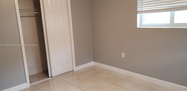 unfurnished bedroom with light tile patterned floors and a closet