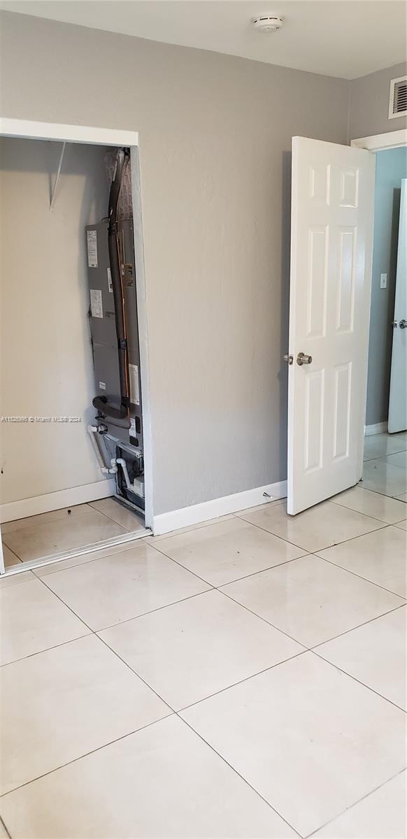 empty room with light tile patterned flooring and heating unit