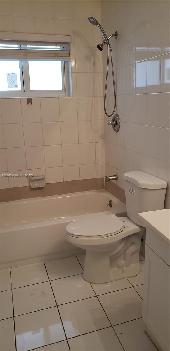 full bathroom featuring tiled shower / bath, vanity, toilet, and tile patterned flooring