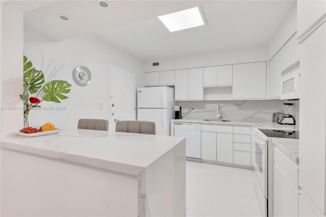 kitchen with sink, white cabinetry, white appliances, and kitchen peninsula