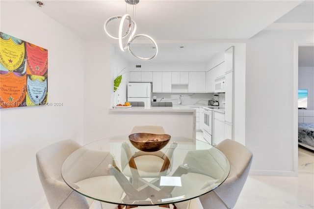 dining room with an inviting chandelier, sink, and light tile floors