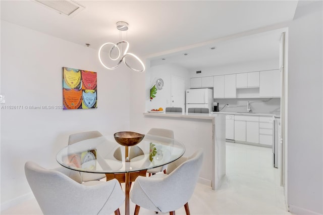 dining room featuring sink, a chandelier, and light tile floors