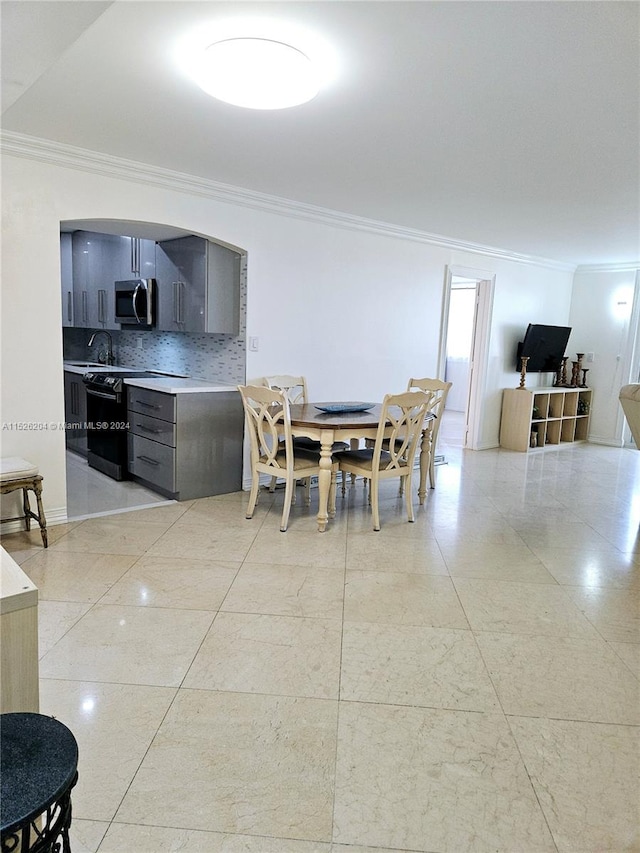 dining space featuring sink, crown molding, and light tile flooring