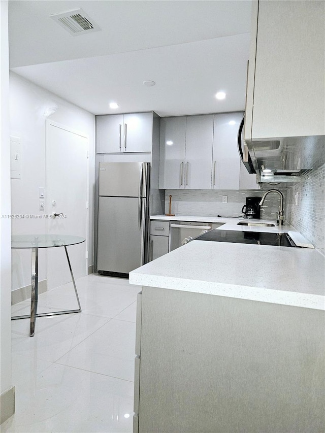 kitchen with backsplash, appliances with stainless steel finishes, sink, light tile floors, and gray cabinets